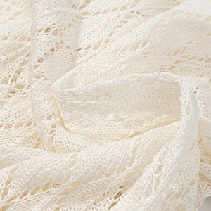 Macro shot of cream lace hollow knit fabric texture and intricate crochet embroidery