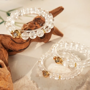 Detailed macro view of white crystal beaded bracelets with gold accents on zen stone background