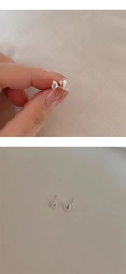 Detailed view of small s925 silver heart studs held in fingers for size reference
