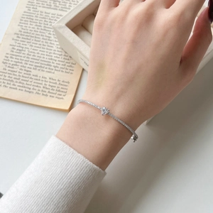 Macro detail of silver heart-shaped gemstone bracelet with pavé diamonds on model wrist