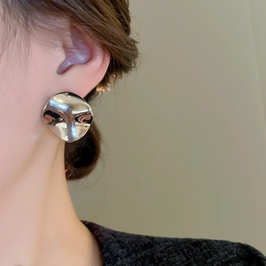 Detailed view of large irregular metallic silver earring with smooth mirror finish texture