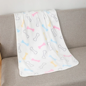 Detailed texture of thick flannel pet blanket with colorful bone patterns on sofa