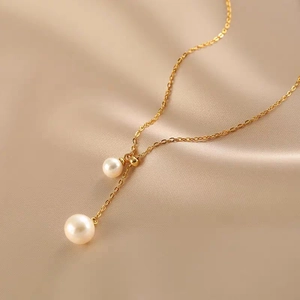 Elegant gold titanium necklace with pearl pendants and Y-shape design on beige silk