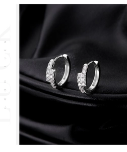 Macro shot of double-row VVS1 moissanite hoop earrings on black leather texture