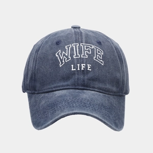 Close-up of WIFE LIFE embroidery on washed blue denim baseball cap with vintage texture