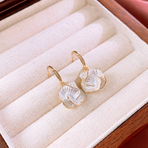 Detail of gold flower earrings with white petals and zircon studs in a wooden box