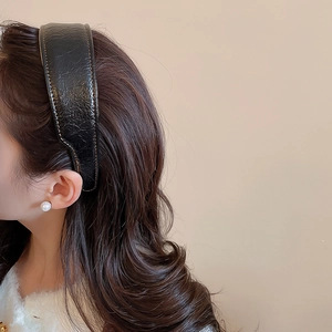 Detail of black pleated leather headband with yellow stitching on high-crown design