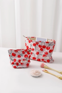 Detail of red cherry printed canvas cosmetic bag set with zipper and brand label