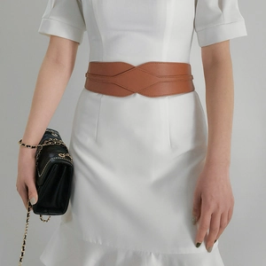Close-up of elegant brown leather wide corset belt styled on a white dress for women