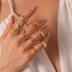 Primo piano di un set di 16 anelli d'oro geometrici indossati da una modella