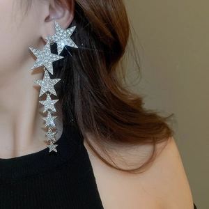 Close-up of cascading silver star earrings with pavé crystals on a female model