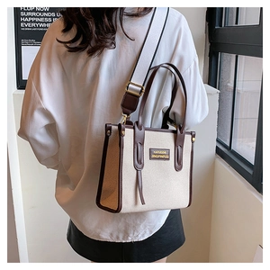 Canvas tote bag in beige and brown leather showing shoulder strap detail on model