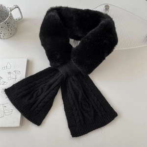Detail of black faux fur and knit scarf with criss-cross design on a white surface