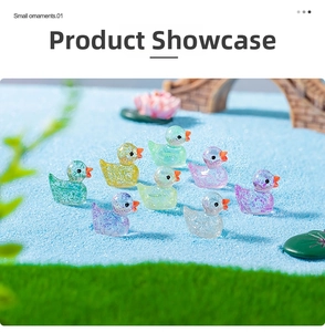 Miniature resin glitter ducks in various colors placed on a blue sand micro landscape
