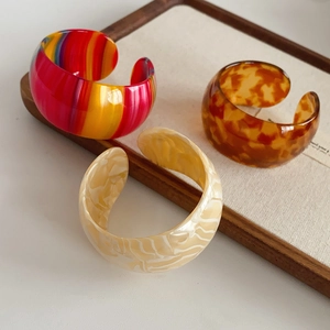 Detailed view of colorful acetate resin cuff bracelets in rainbow, amber, and marble patterns