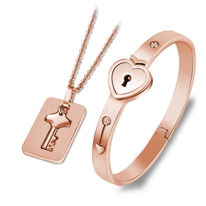 Macro detail of rose gold heart lock bangle and key necklace set with crystal accents