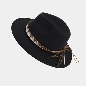Detalle de sombrero de lana negra con banda trenzada marrón y cordones con borlas