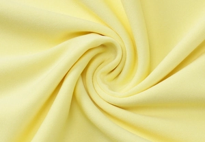 Vista macro di un tessuto giallo pallido con una consistenza morbida e dettagli di trama