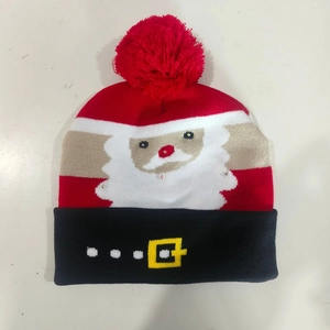 Detail view of knitted Christmas hat with red pom-pom and Santa Claus belt buckle pattern