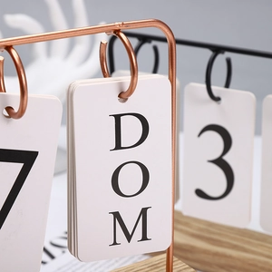 Macro view of Nordic wooden calendar featuring copper wire frame and hanging date cards