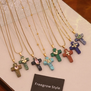 Detail view of colorful cross necklaces with natural stone texture and gold metal chain
