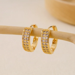 Macro detail of gold huggie earrings with triple-row pavé zircon on natural branches