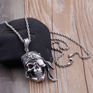 Détail du pendentif crâne de pirate avec œil en pierre rouge sur chaîne corde