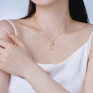 Close-up of a gold-toned fish pendant necklace with white zircon accents on a model