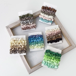 Set of satin silk scrunchies in various pastel colors displayed on white cards