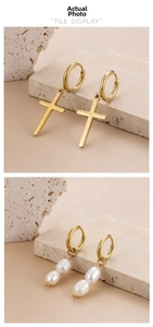 Detail of gold titanium hoop earrings with cross pendant and baroque pearl drop charms