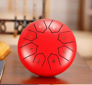 Top view of a red 8-note steel tongue drum with golden numbered musical scale symbols