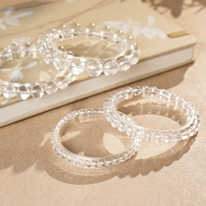 Detailed view of clear white crystal beaded bracelets on a vintage notebook with soft shadows