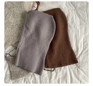 Flat lay of gray and brown knitted balaclava hats with drawstring on white texture