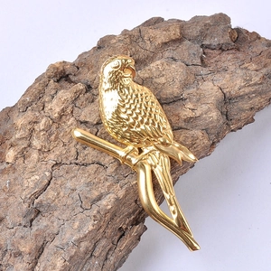 Macro shot of gold bird brooch showing detailed feather texture and metallic branch