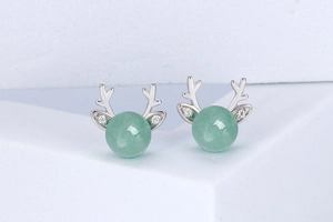 Macro shot of silver deer antler earrings with green aventurine beads and sparkling zircons