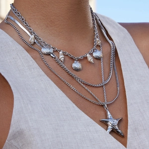 Layered stainless steel necklace set with silver shell and starfish charms on a model