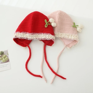 Detailed view of handmade knitted baby earflap hats with lace trim and tulip accents