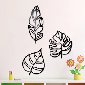 Lot de 3 décorations murales feuilles en métal noir ajouré sur un mur de salon beige
