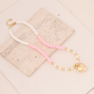 Bohemian clay bead necklace with pearls and gold heart pendant on marble background