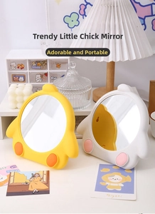 Close-up of yellow and white cartoon chick desktop mirrors with built-in stands on a desk