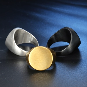 Three signet rings in gold, silver, and black finishes with a brushed metal surface texture