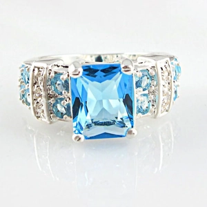 Macro view of wide silver ring band featuring square blue gemstone and pave crystals