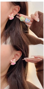 Detail view of plush cartoon earrings in rabbit, heart and bear shapes on ear