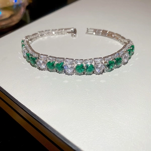 Close-up of silver-tone bracelet with emerald green and white zircon gemstones