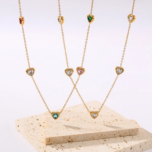Gold-plated heart pendant necklaces with colorful zircon stones on travertine