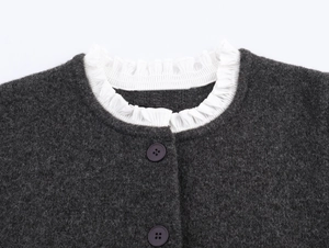 Detail of dark grey knit cardigan collar with white ruffled edges and round buttons