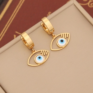 Macro shot of gold evil eye earrings with vibrant blue enamel details on textured surface