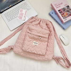 Detailed heart-quilted texture and woven label on a pink plaid drawstring backpack