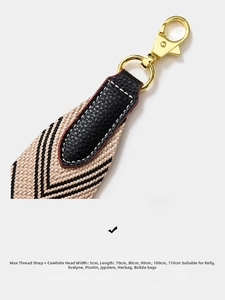 Close-up of 5cm wide beige woven strap with black leather ends and gold metal hooks