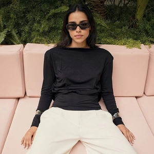 Chic long sleeve black top featuring elegant boat neck design and backless detail